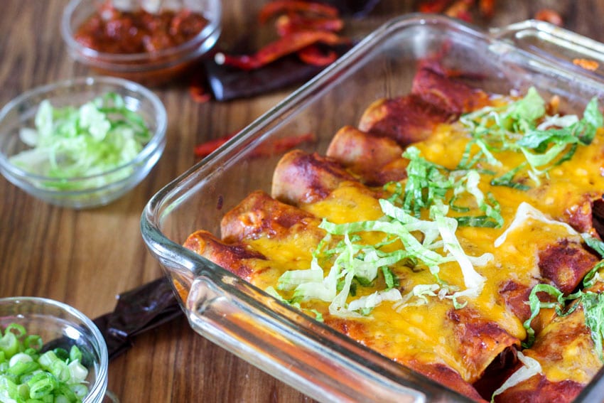close up of enchiladas in pan made with this venison cooked in the slow cooker.