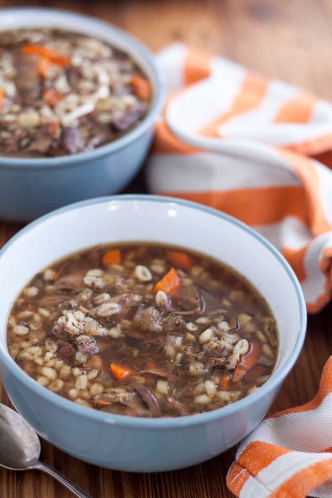 venison soup in grey bowl with orange and white towel background
