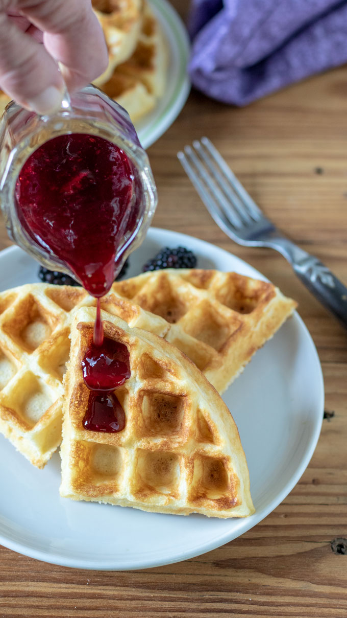 syrup pouring on waffles on white plate