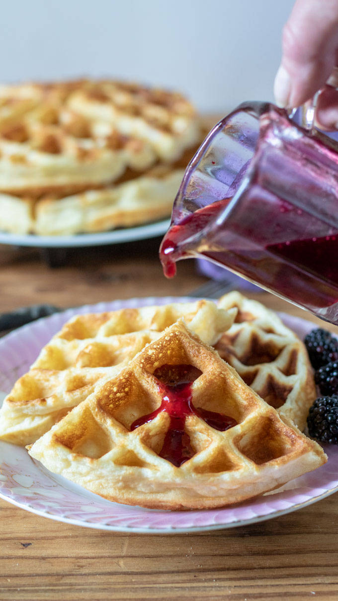 pink antique plate with waffles, hand pouring syrup