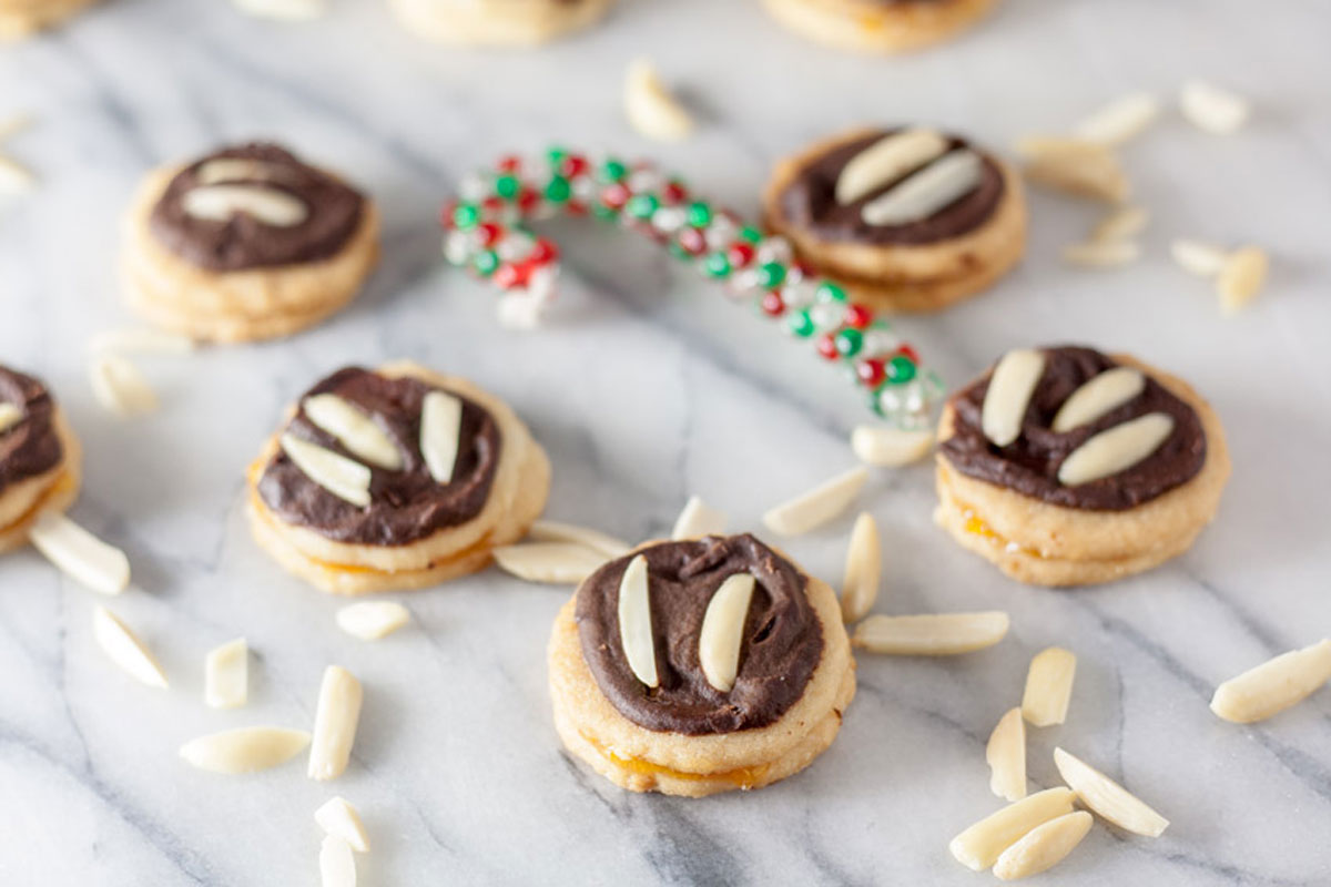 Chocolate covered Ischlers Sandwich Cookie with slivered almonds on top on marble board