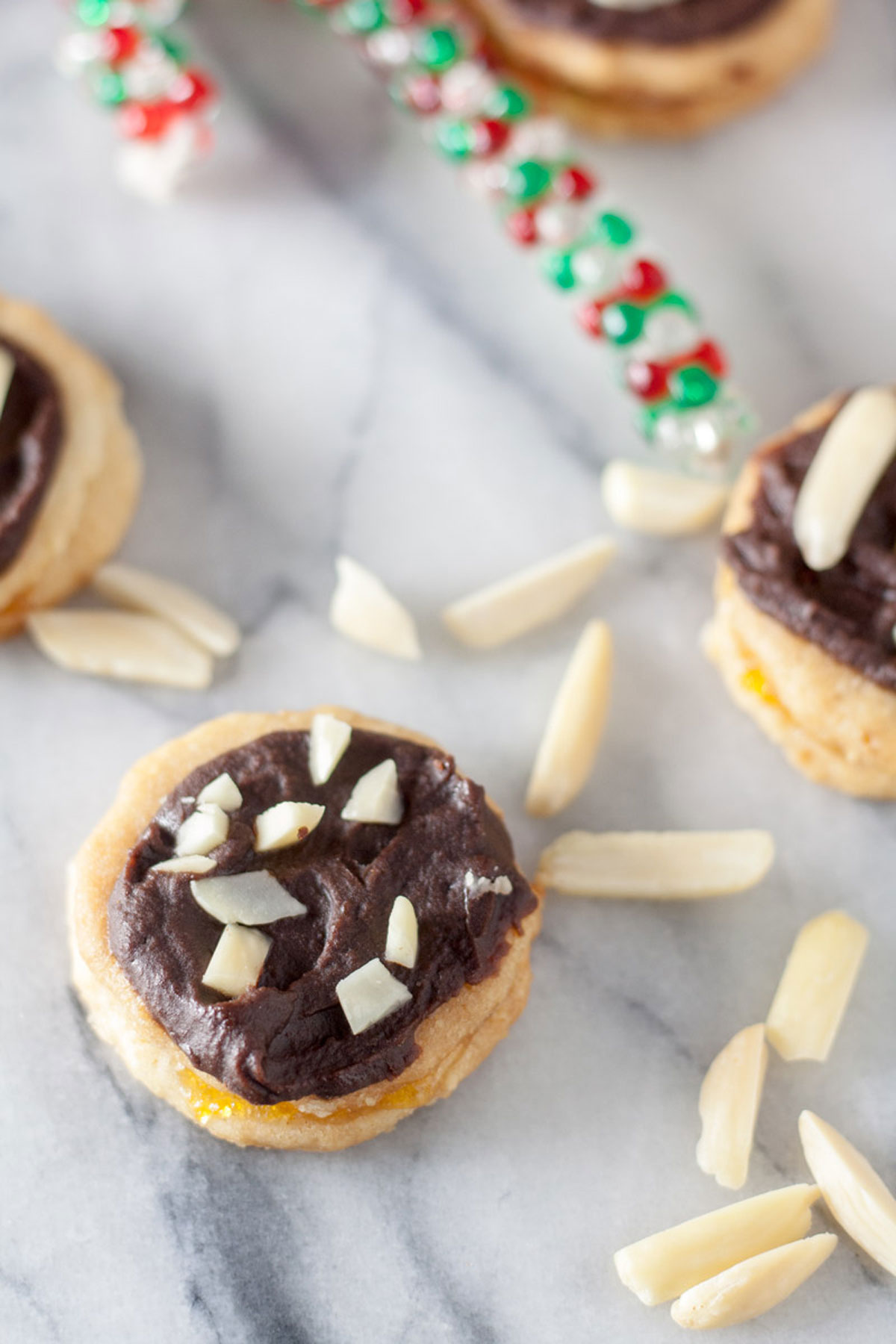 Chocolate covered Ischelers Tortellettes Sandwich Cookie with slivered almonds on marble board