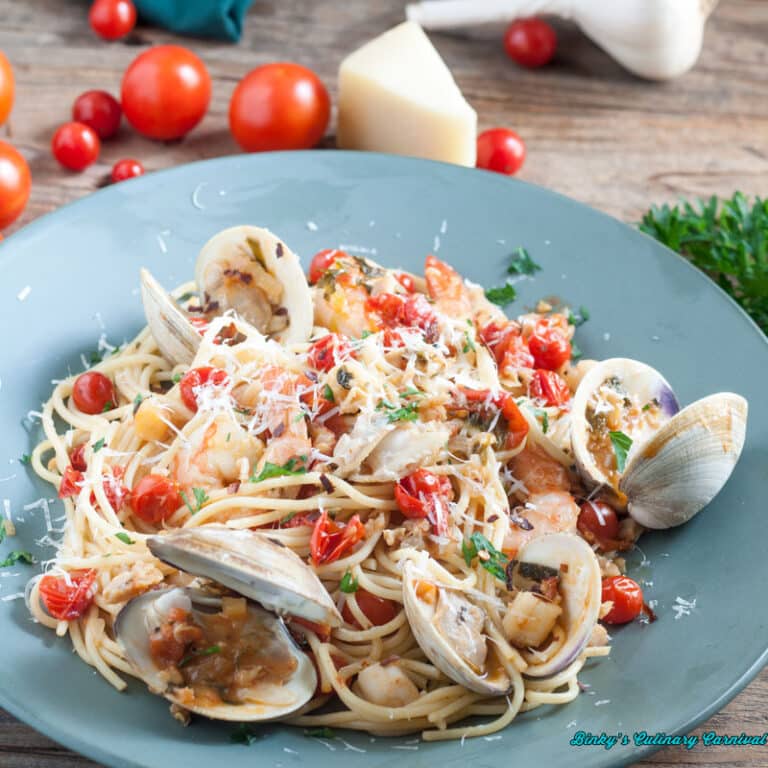 clams, shrimp, scallops in a fresh cherry tomato sauce on blue plate