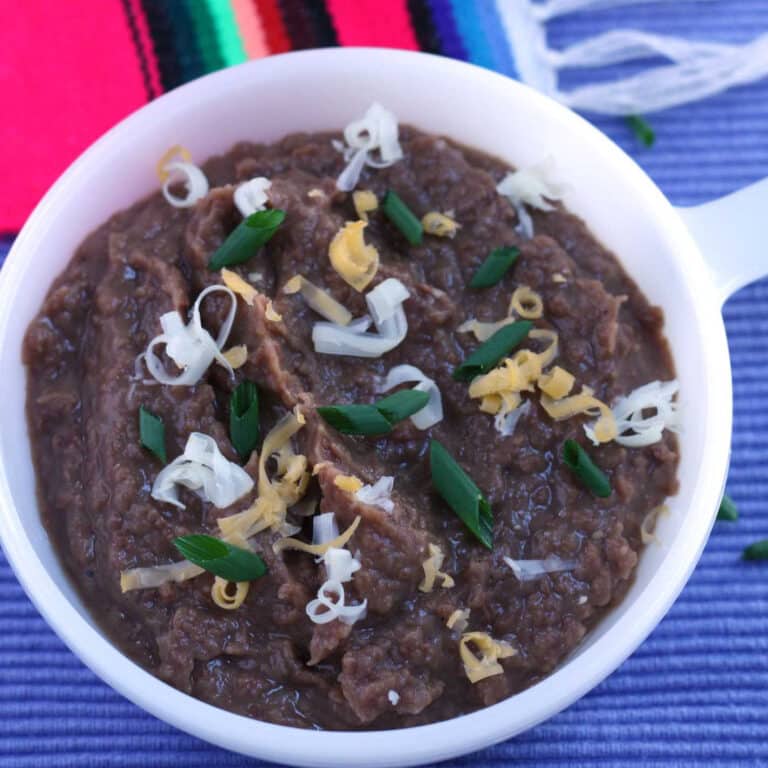 refried beans in white bowl with handle on purple board