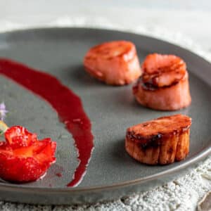 Strawberry infused scallops on gray plate.
