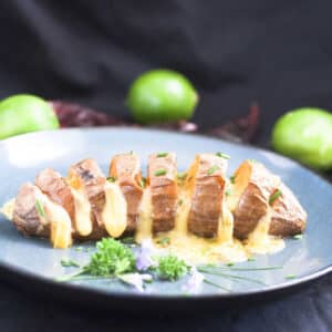cheesy hasselback sweet potato on blue plate