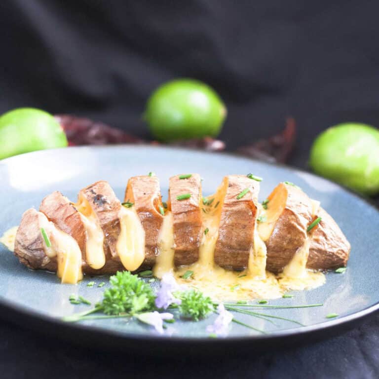 cheesy hasselback sweet potato on blue plate
