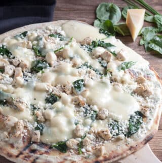 Thin Crust Chicken Pizza with Feta & Spinach on a wooden pizza peel