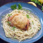 lemon chicken atop pasta on blue plate