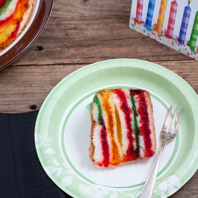 Colorful Rainbow Cake on white plate with green trim