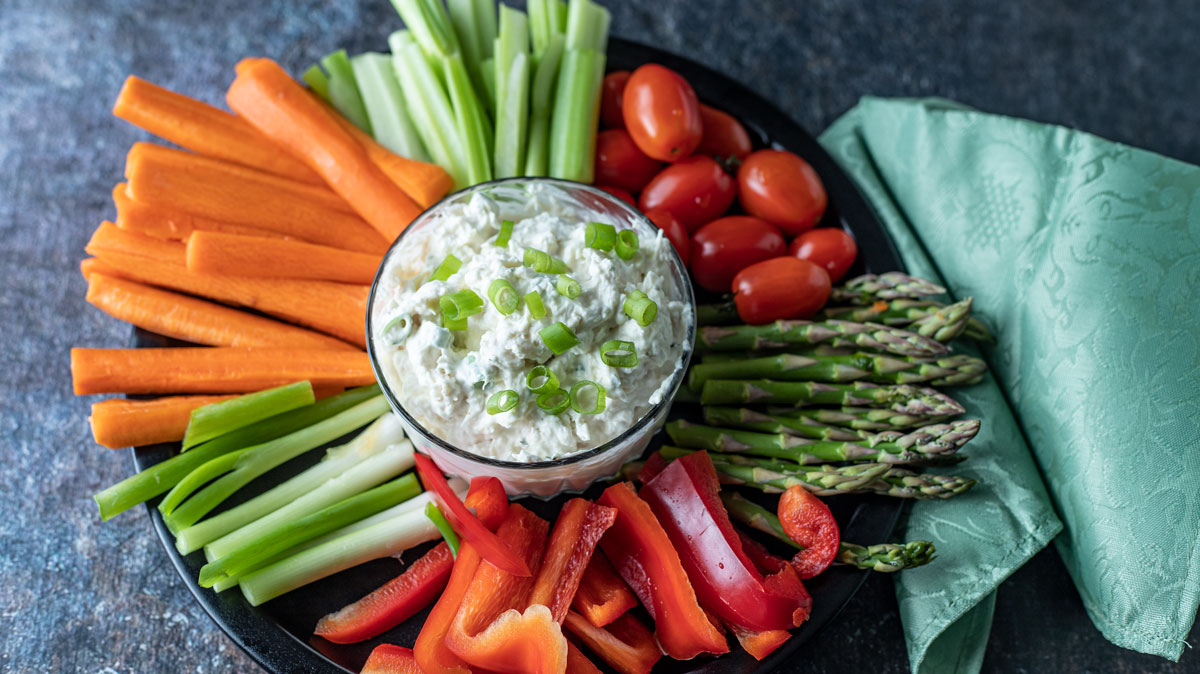 Seafood dip in glass bowl with julienned vegetables.