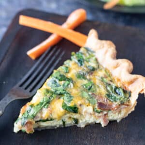 Slice of quiche on wooden plate.