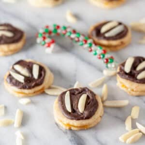 Chocolate covered, almond topped cookies with apricot filling on marble board