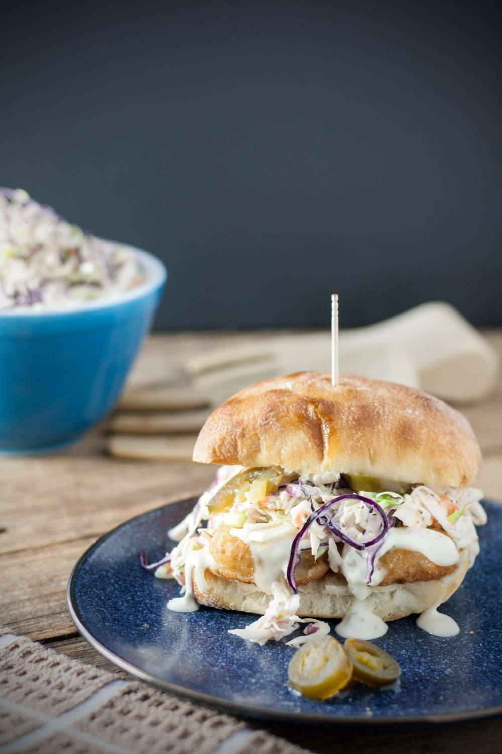 Spicy fish sandwich on a blue plate.