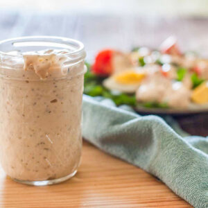 Thousand island dressing in a canning jar with a salad in the background.