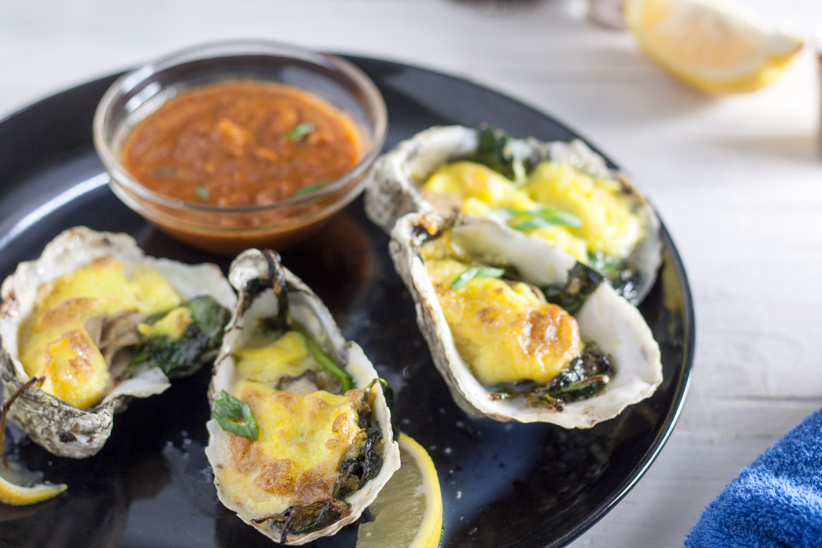 Oysters Rockefeller on a black serving plate.