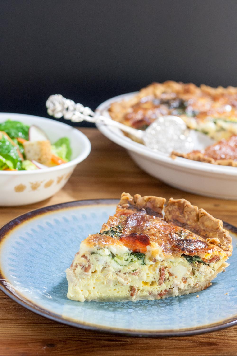 Slice of chicken quiche on a blue plate.
