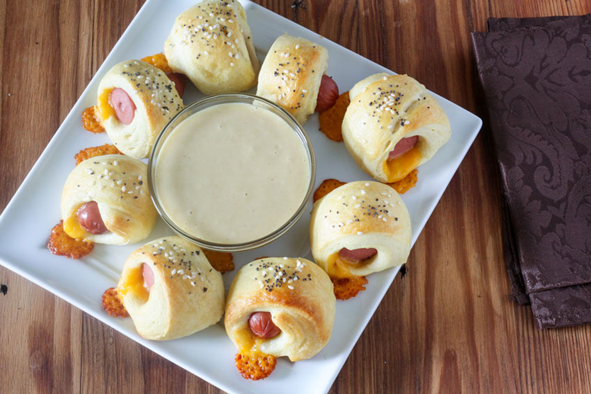 Square white plate with pigs in a blanket and dipping sauce