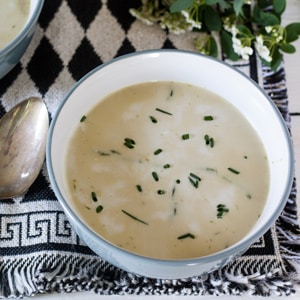 asparagus soup in white and gray bowl garnished with chives.