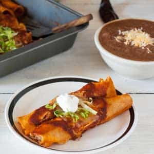 2 chicken enchiladas garnished with lettuce and sour cream