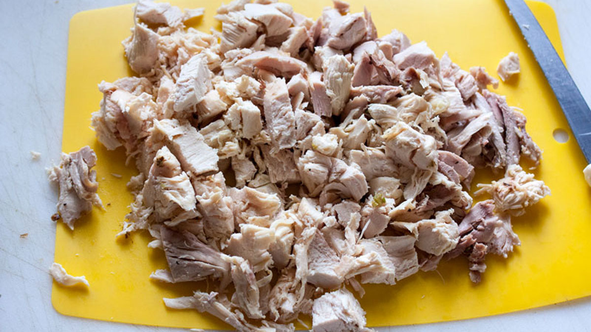 Cooked chicken cut up on board.
