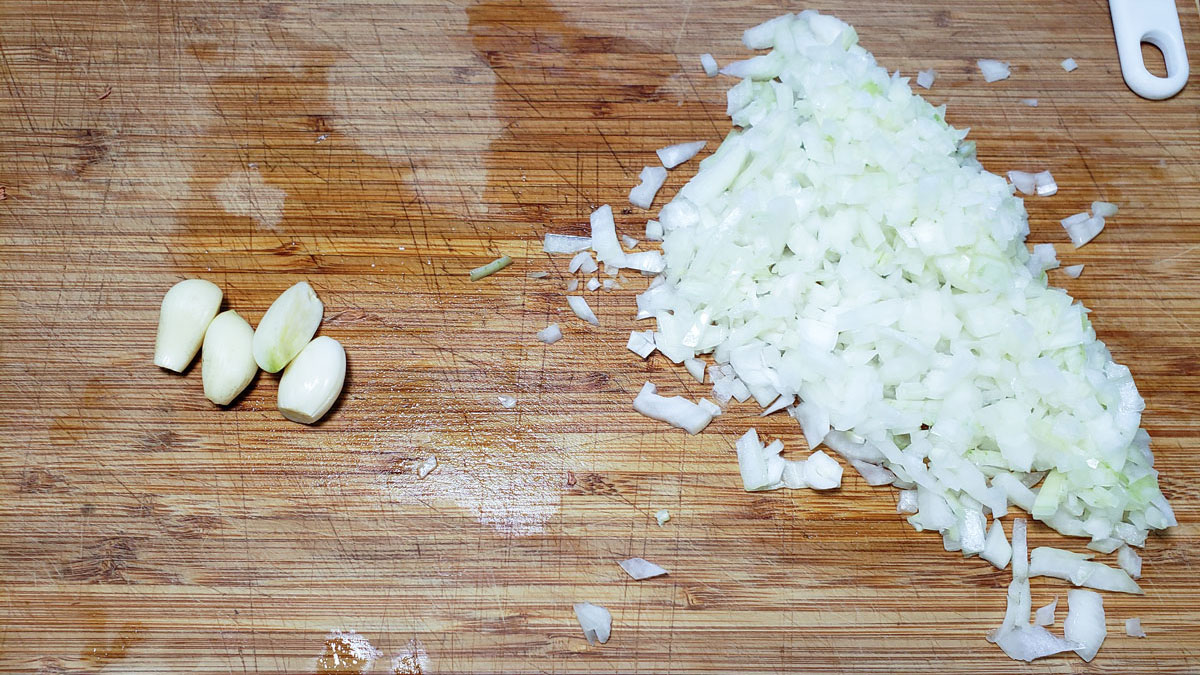 Chopped onion and garlic on a board.