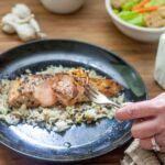 Woman's hand holding a fork with a piece of garlic butter seared salmon.