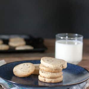 Pecan sandies cookies on dark blue plate with glass of milk