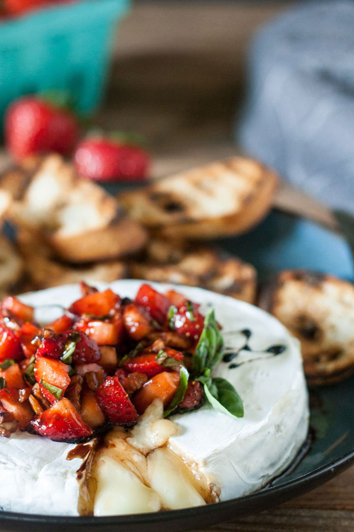 Grilled brie appetizer with balsamic strawberries and toasted crostini.