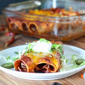venison carnitas in the slow cooker made into enchiladas with lettuce and sour cream garnish