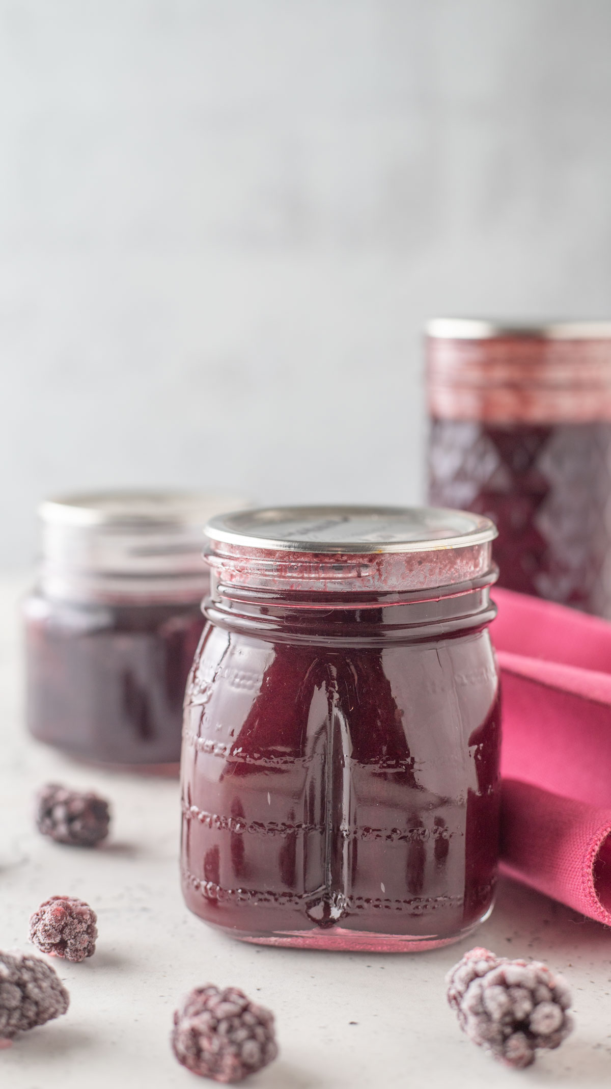 Jars of blackberry syrup with pink towel.