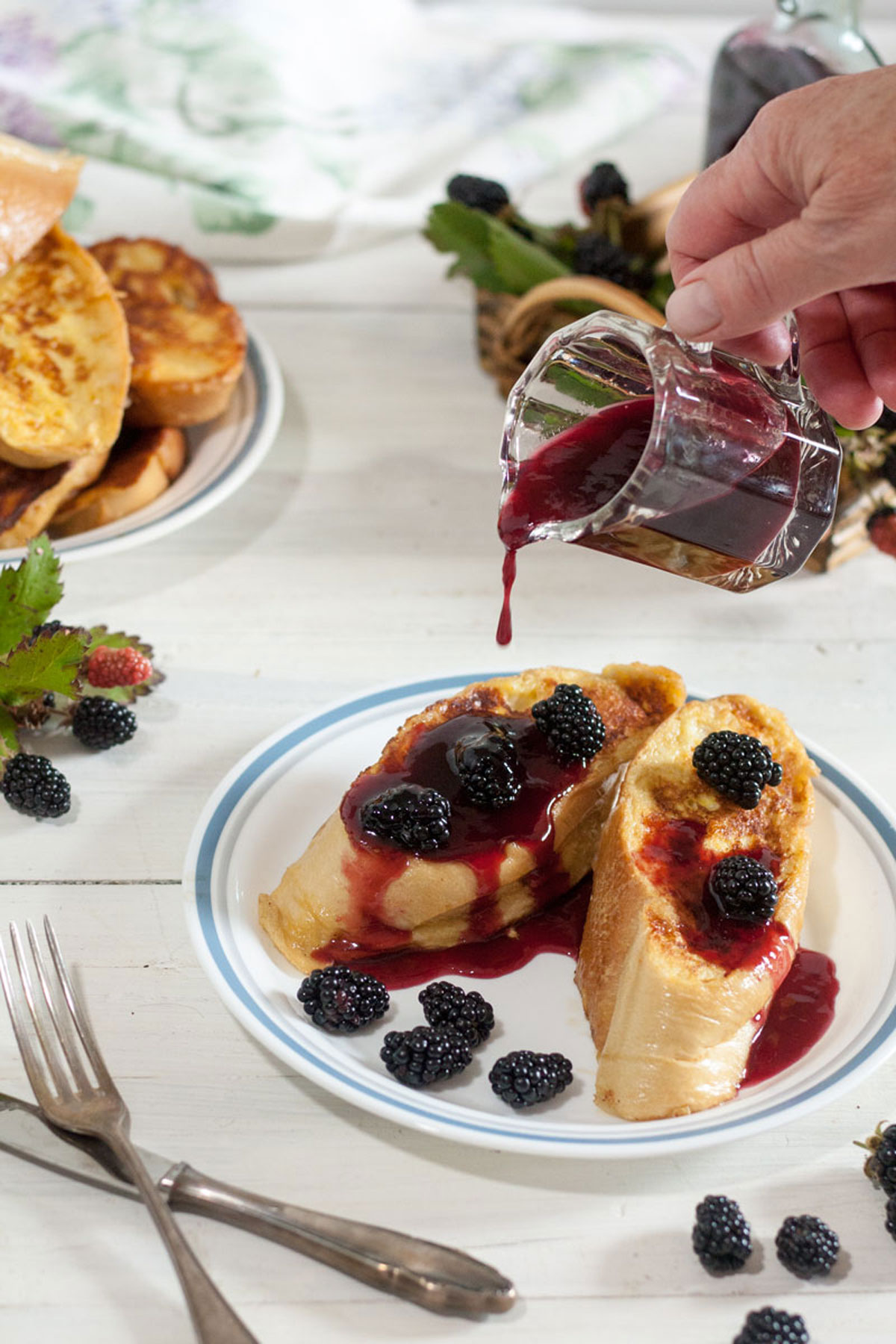 Woman's hand pouring blackberry syrup from small pitcher