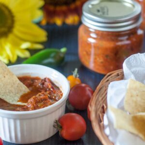 Bowl of salsa next to a basket of chips.