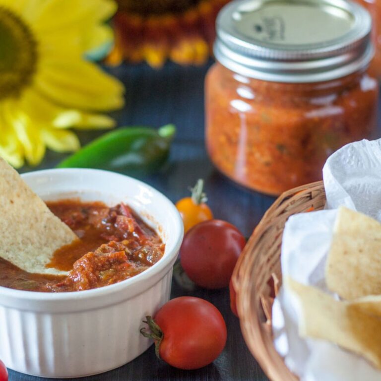 Bowl of salsa next to a basket of chips.