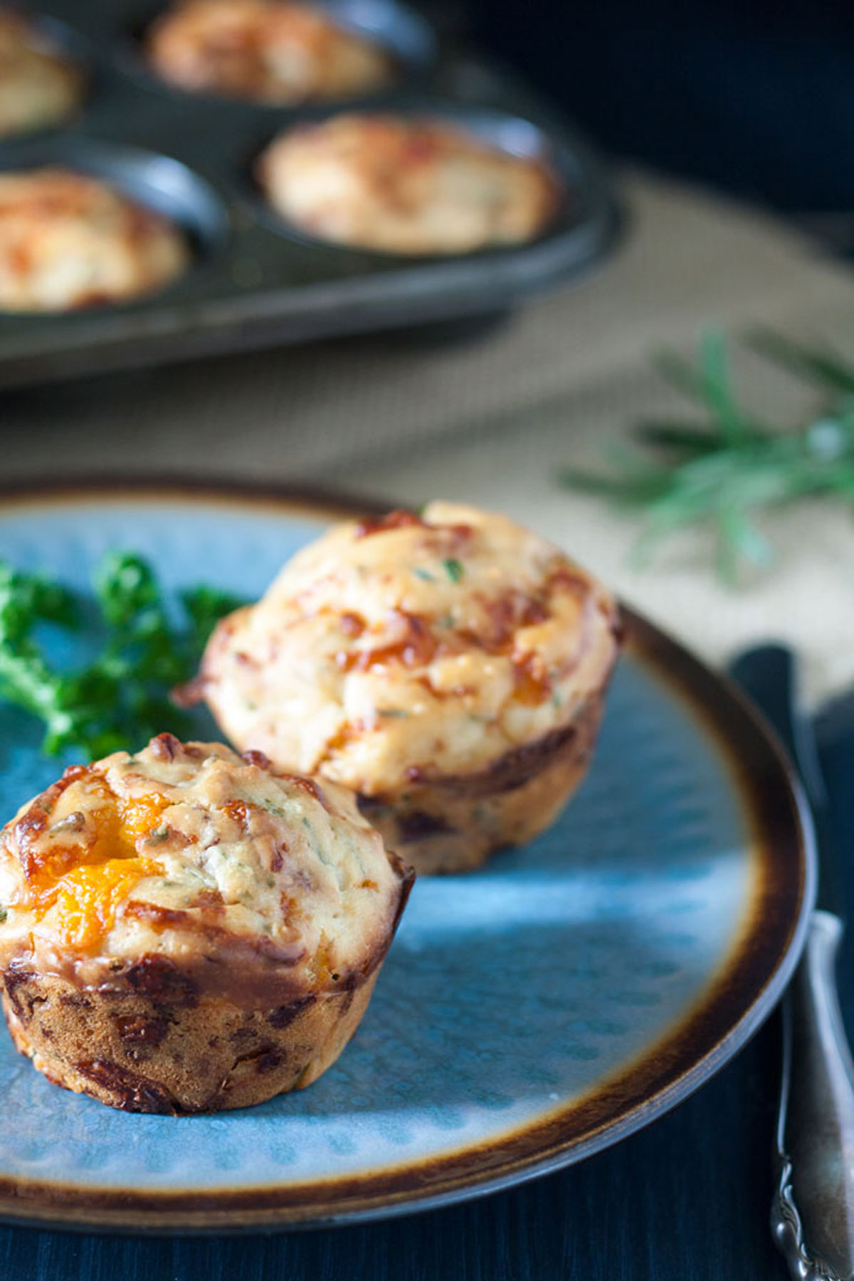 Cheesy Herbed Bacon Muffins on blue plate with herb garnish