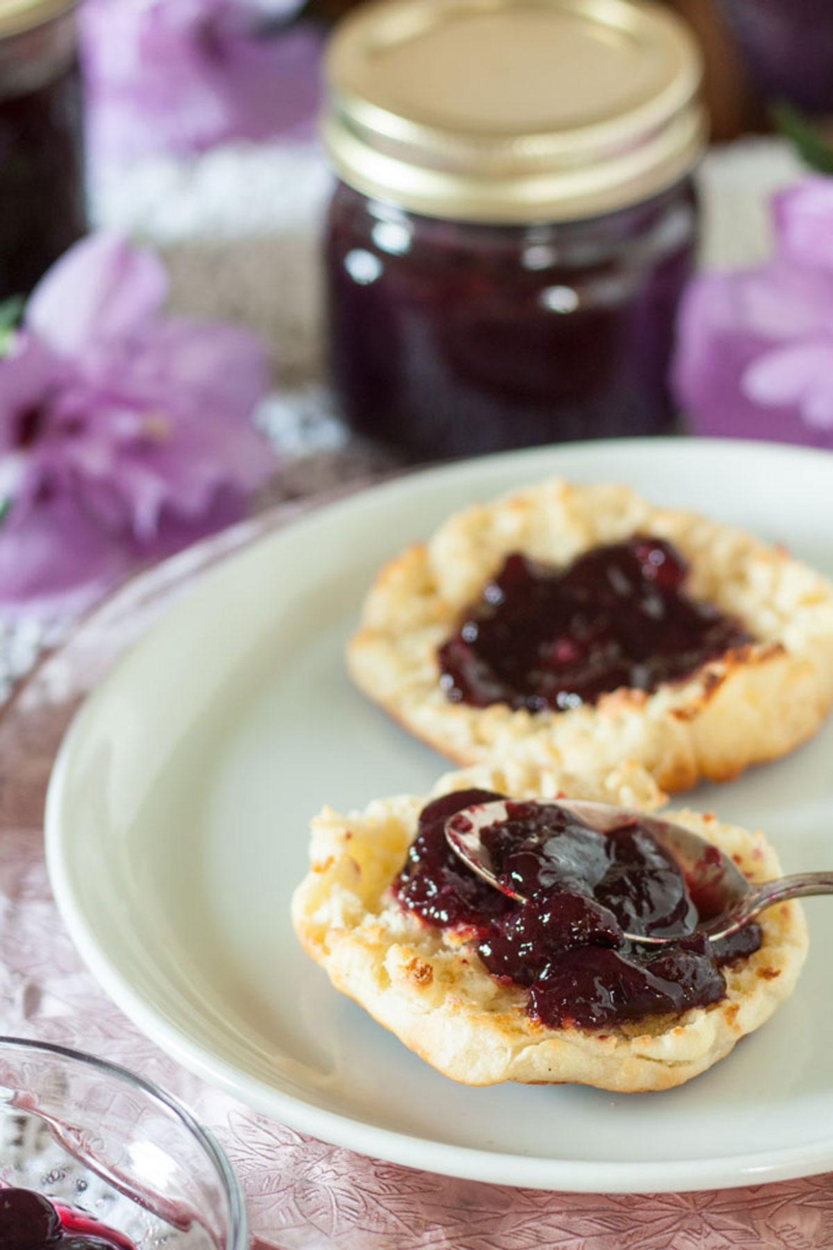 Spooning blackberry jam on English muffin