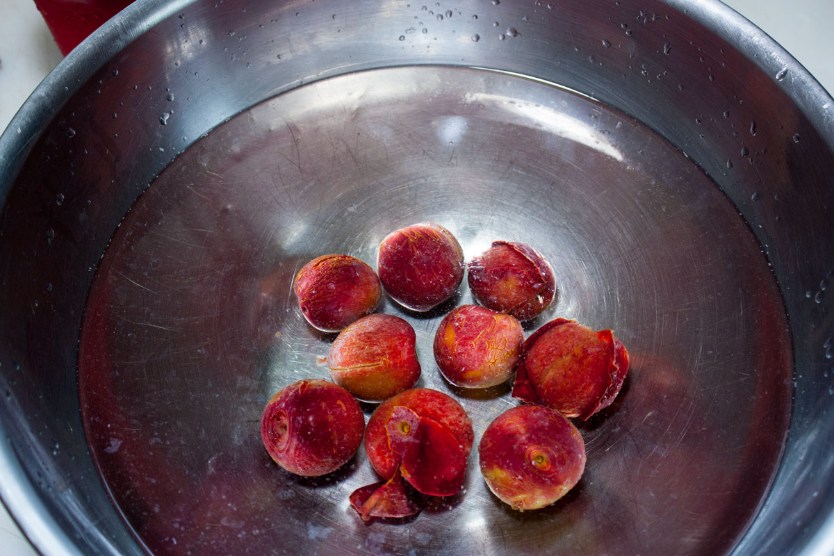 Plums after blanching in a large bowl.