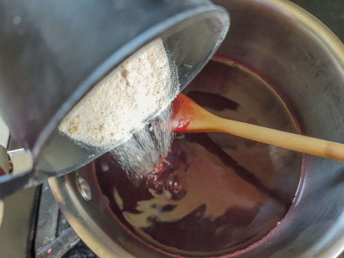 Pouring the pectin mixture into the hot jam.