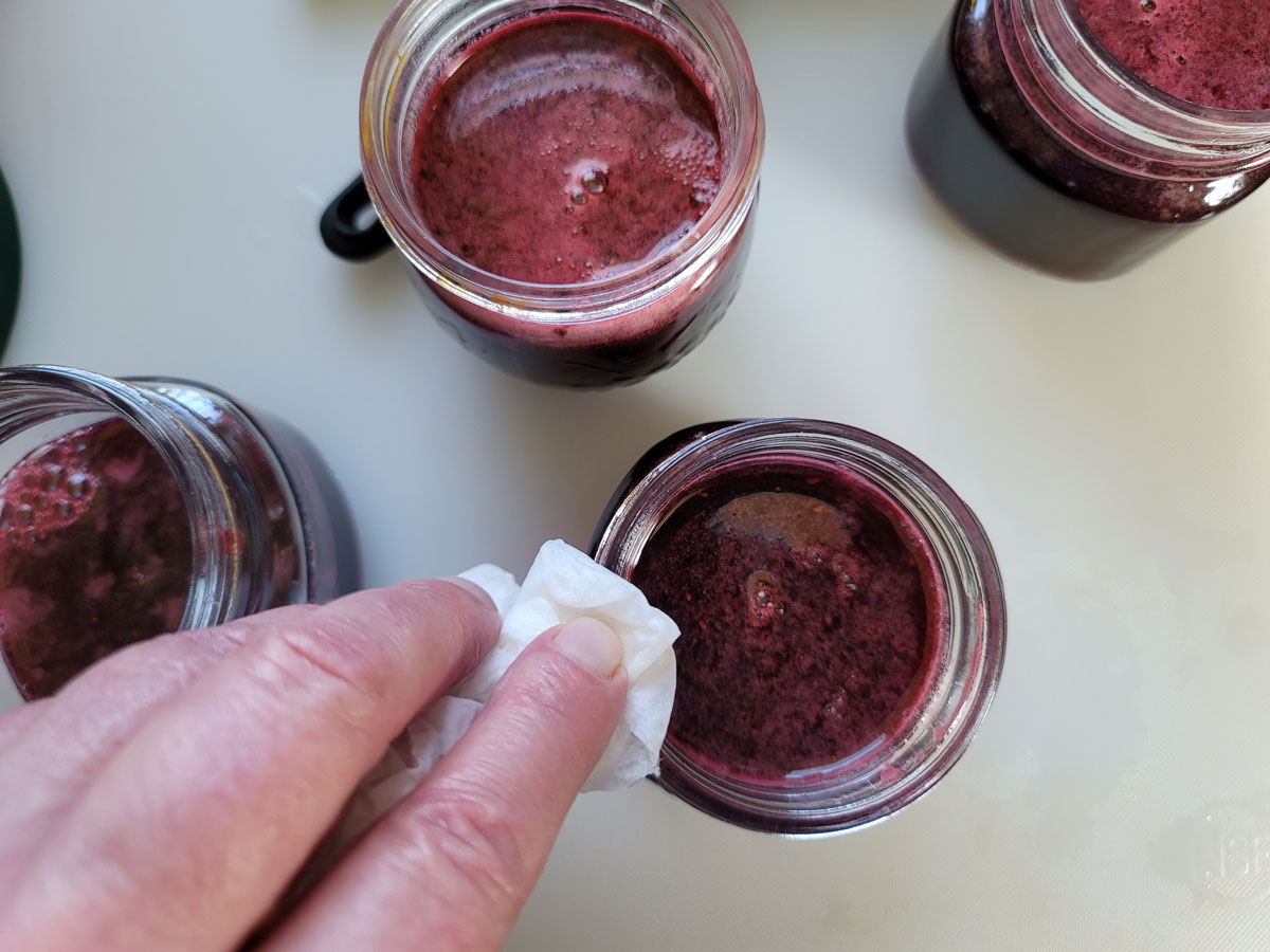 Wiping the rim of the jar with a paper towel.