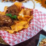 Crispy crusted catfish with sweet potato chips in a basket with red and white checked paper.