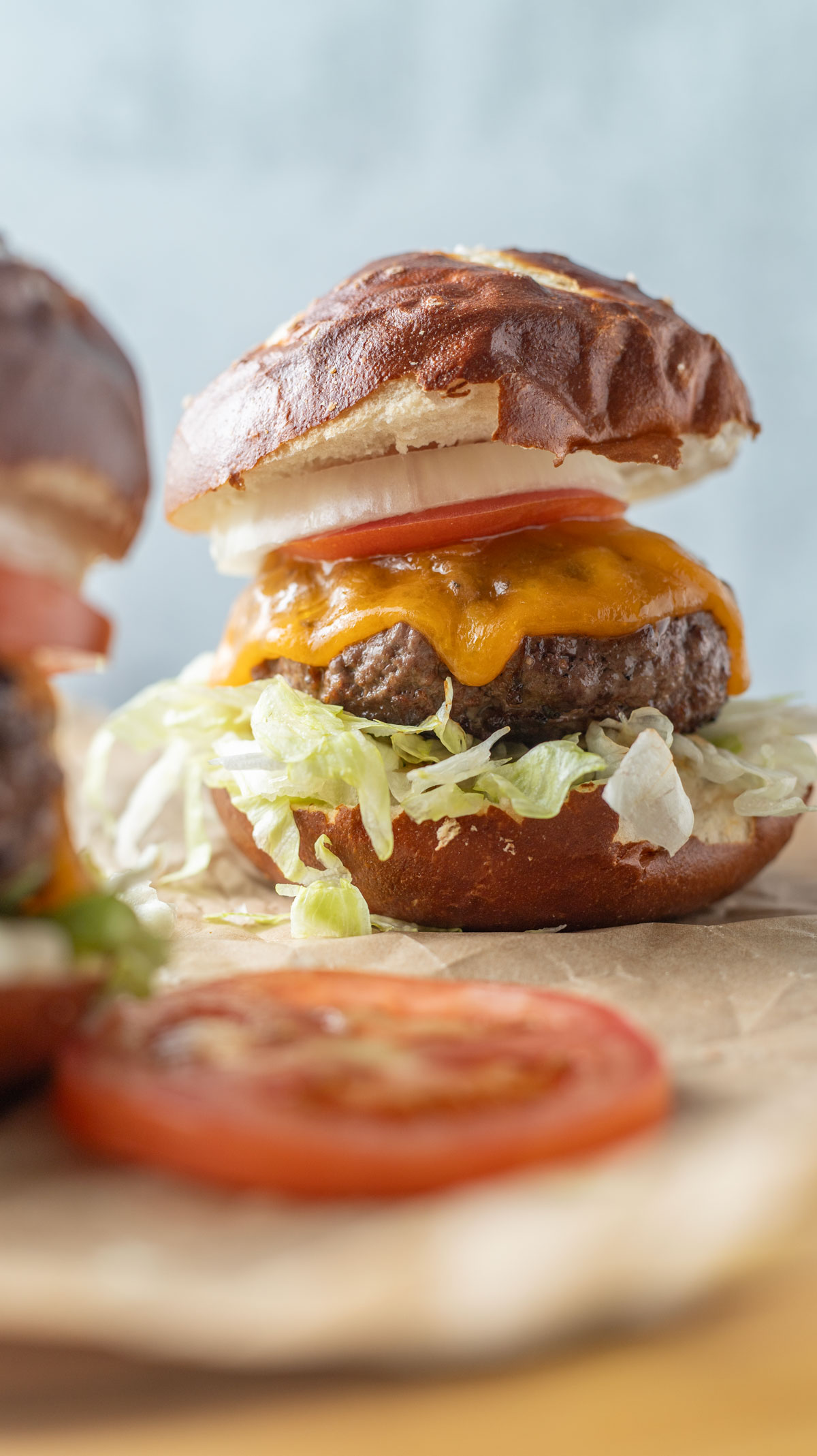 Venison burger with toppings on a pretzel bun.