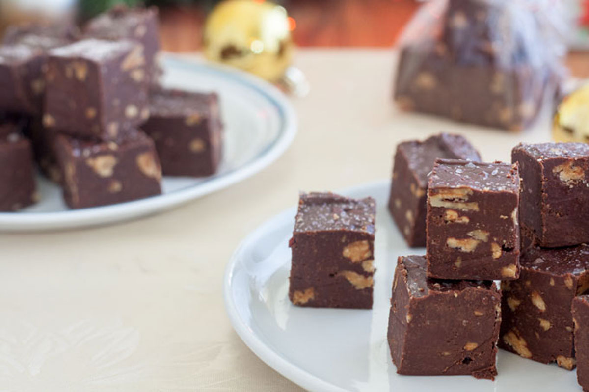 Chocolate fudge on white plates with Christmas decorations in photo.