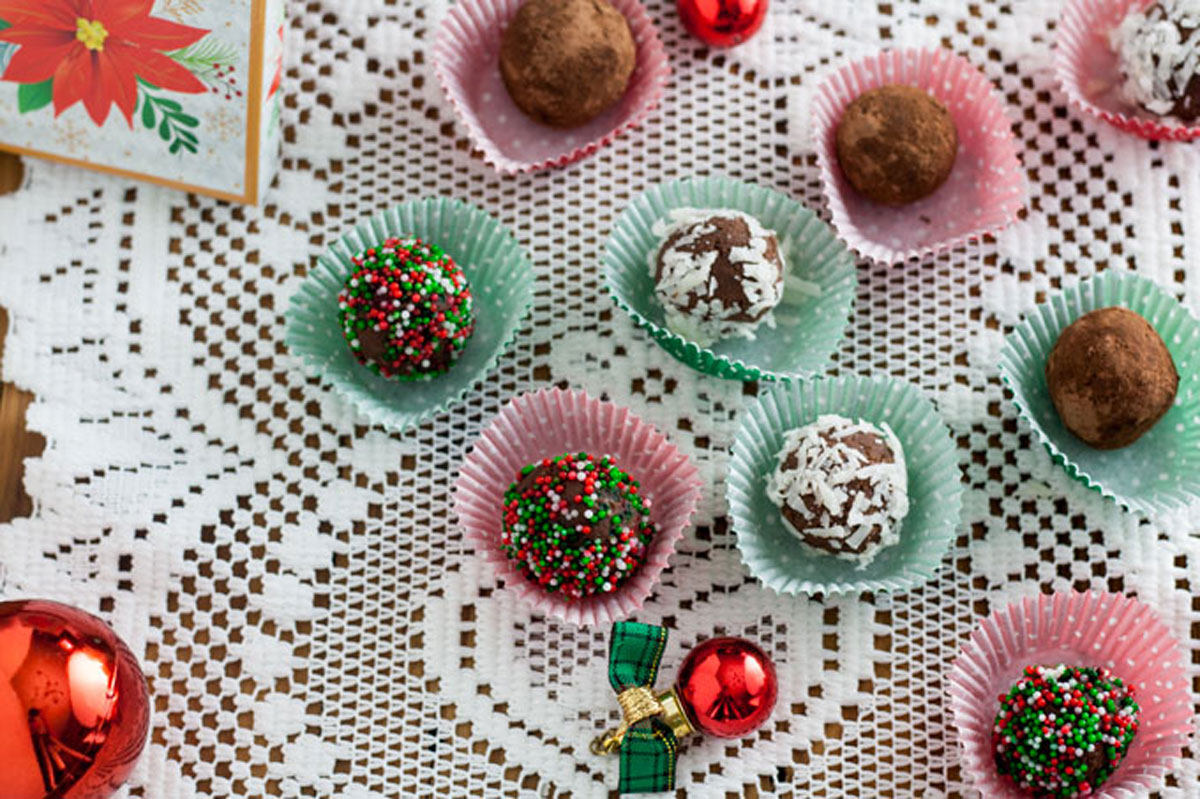 Mini chocolate truffles in red and green decorative mini cups with Christmas decorations.