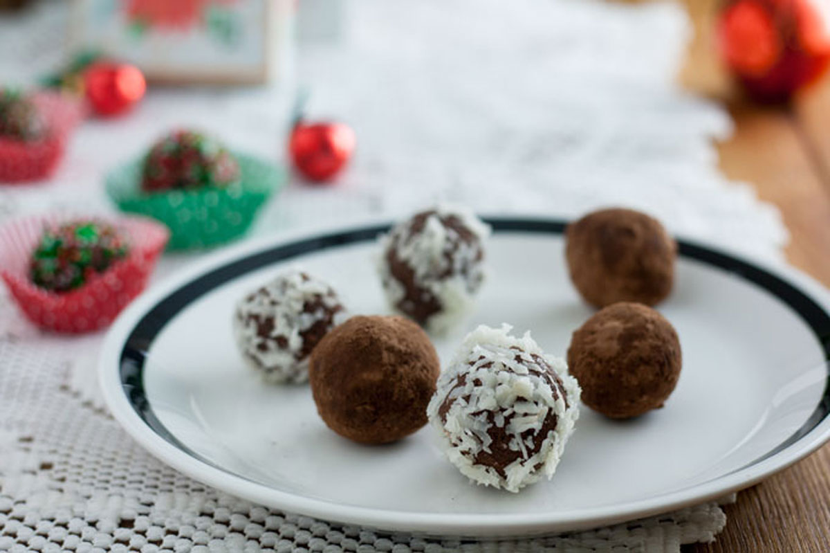 Close up cocoa covered chocolate truffle on white plate with black rim.