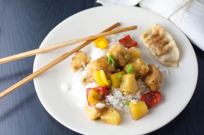 Colorful sweet and sour chicken on a white plate with chopsticks.