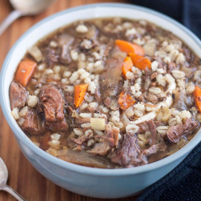 Gray bowl filled with hearty venison soup with vegetables and barley.