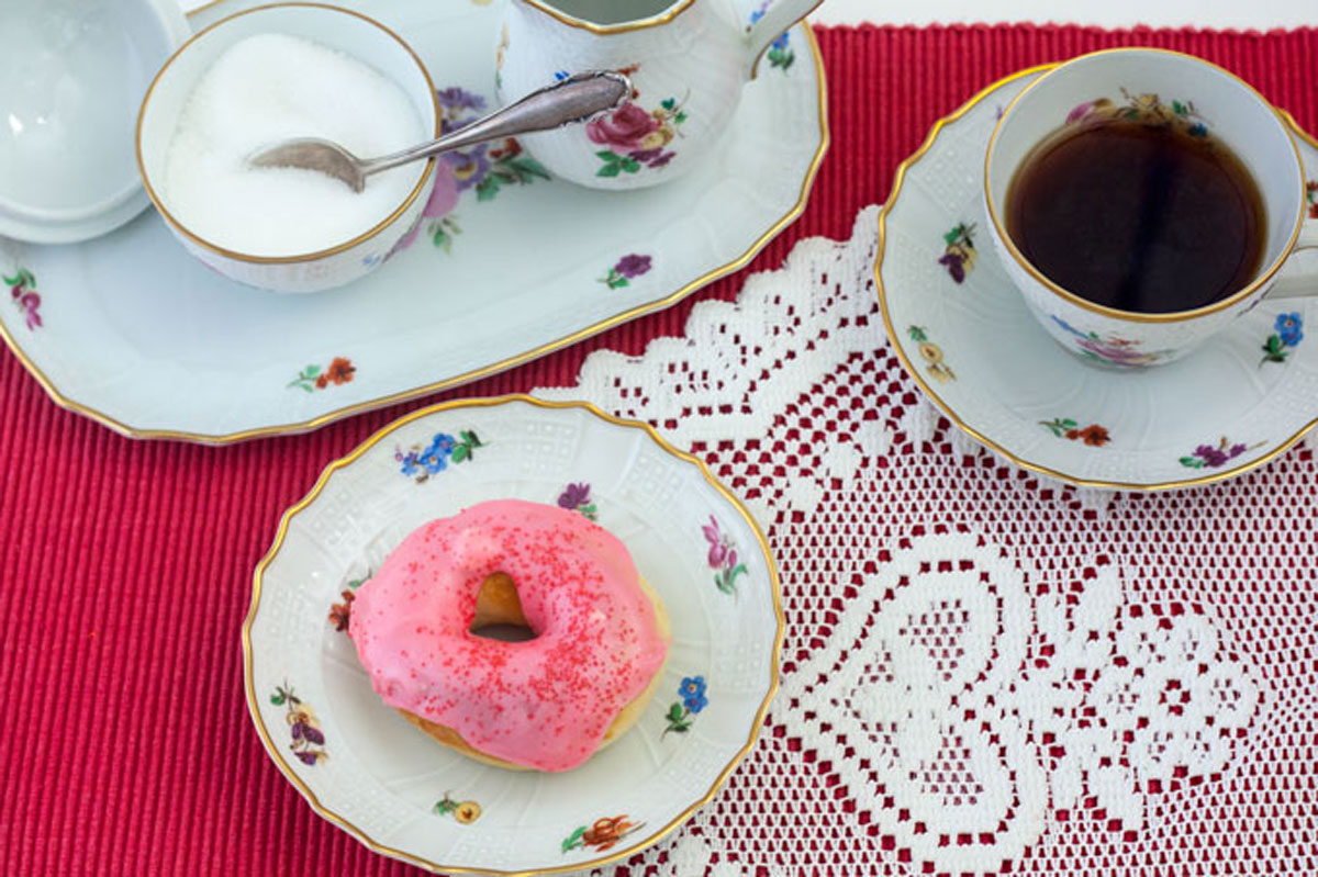 Pink frosted doughnut on antique, flowered china plate