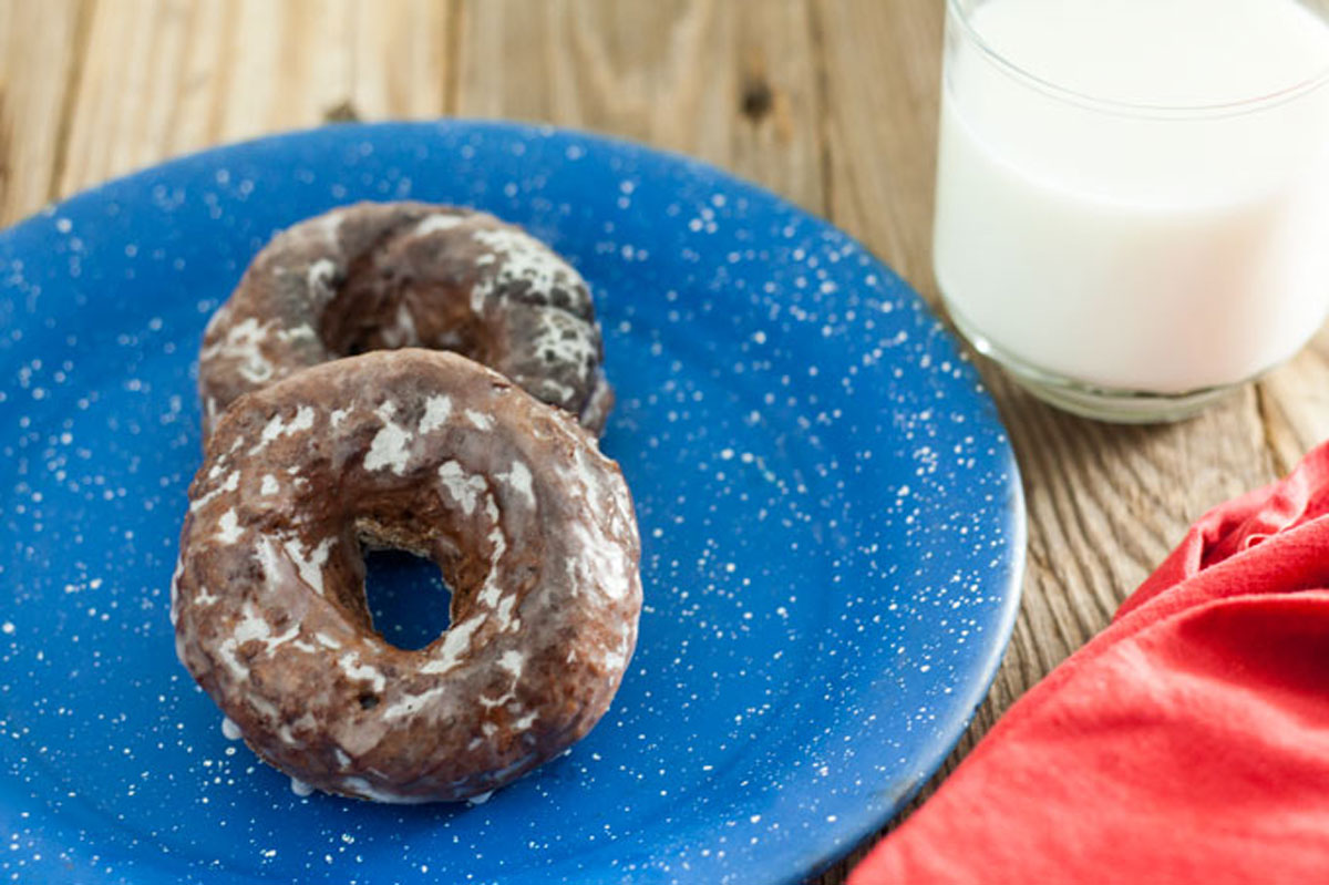 Close up chocolate glazed doughnut on blue plate.