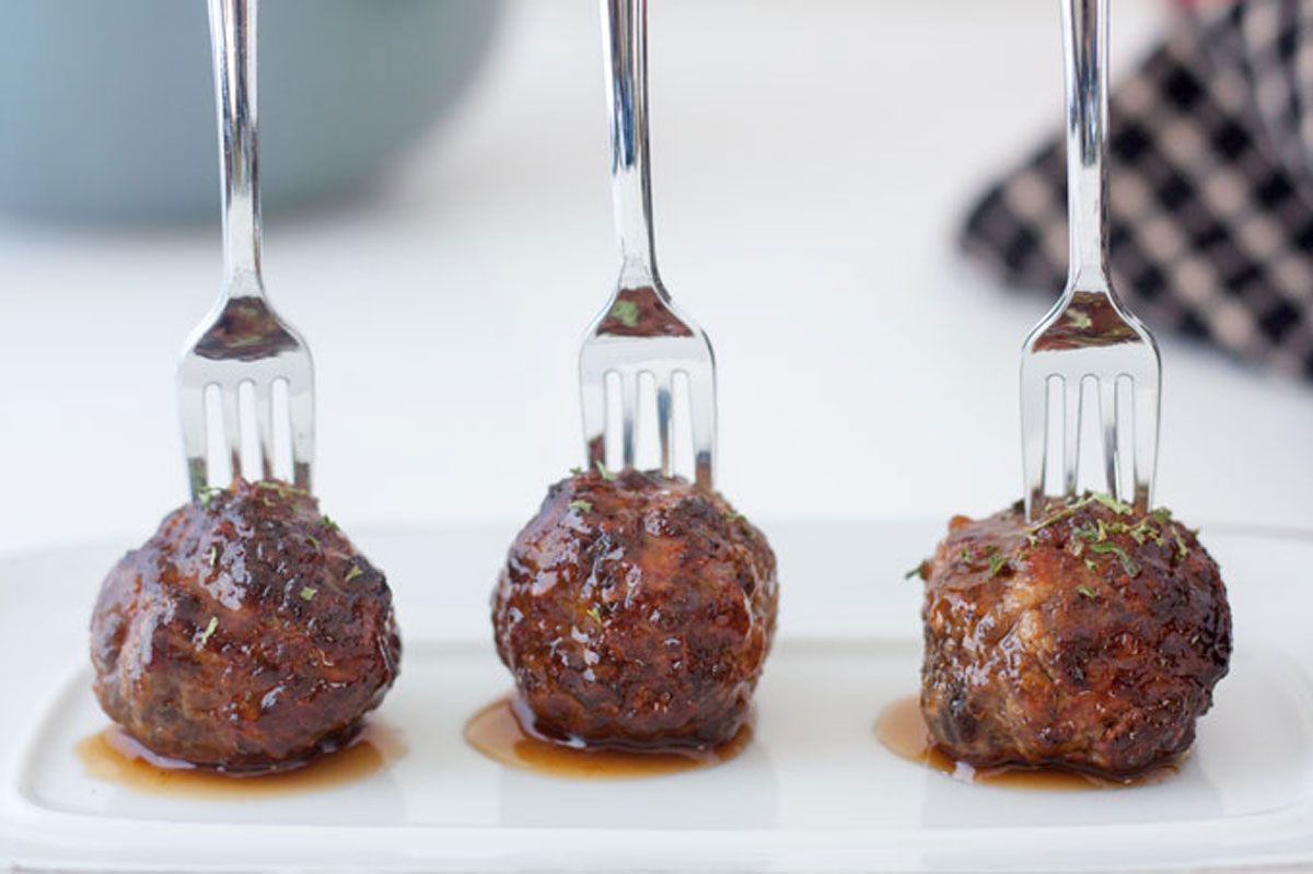 Meatballs on white plate with bowl of meatballs in background