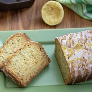 Slices of lemon zucchini bread on a green rectangular tray next to the loaf.